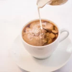 Į kavą pilamas pienas