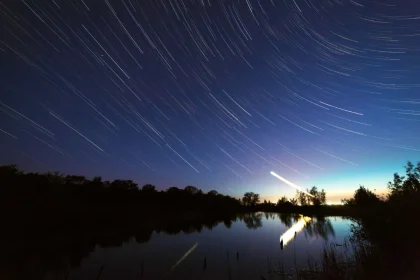 Leonidų meteorų lietus. Ilgas išlaikymas sukuria šviesos takus, atspindžiai vandenyje.